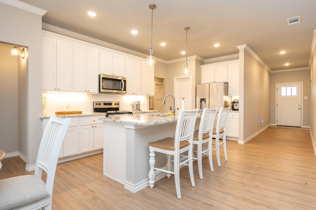 Bright open-concept kitchen with white cabinetry and a large island in a Wall, Texas home